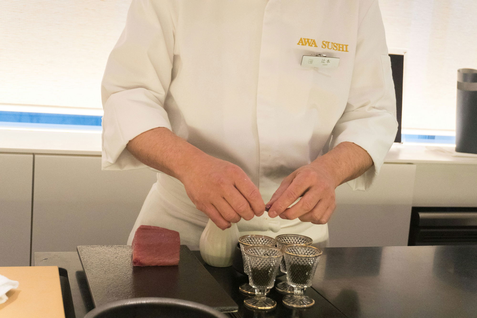 A woman in a chef's coat is putting something in a bowl